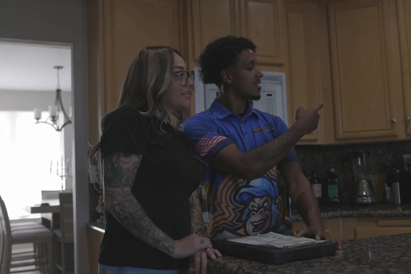 A Monkey Wrench technician talking through a drain problem with a homeowner in a Las Vegas kitchen