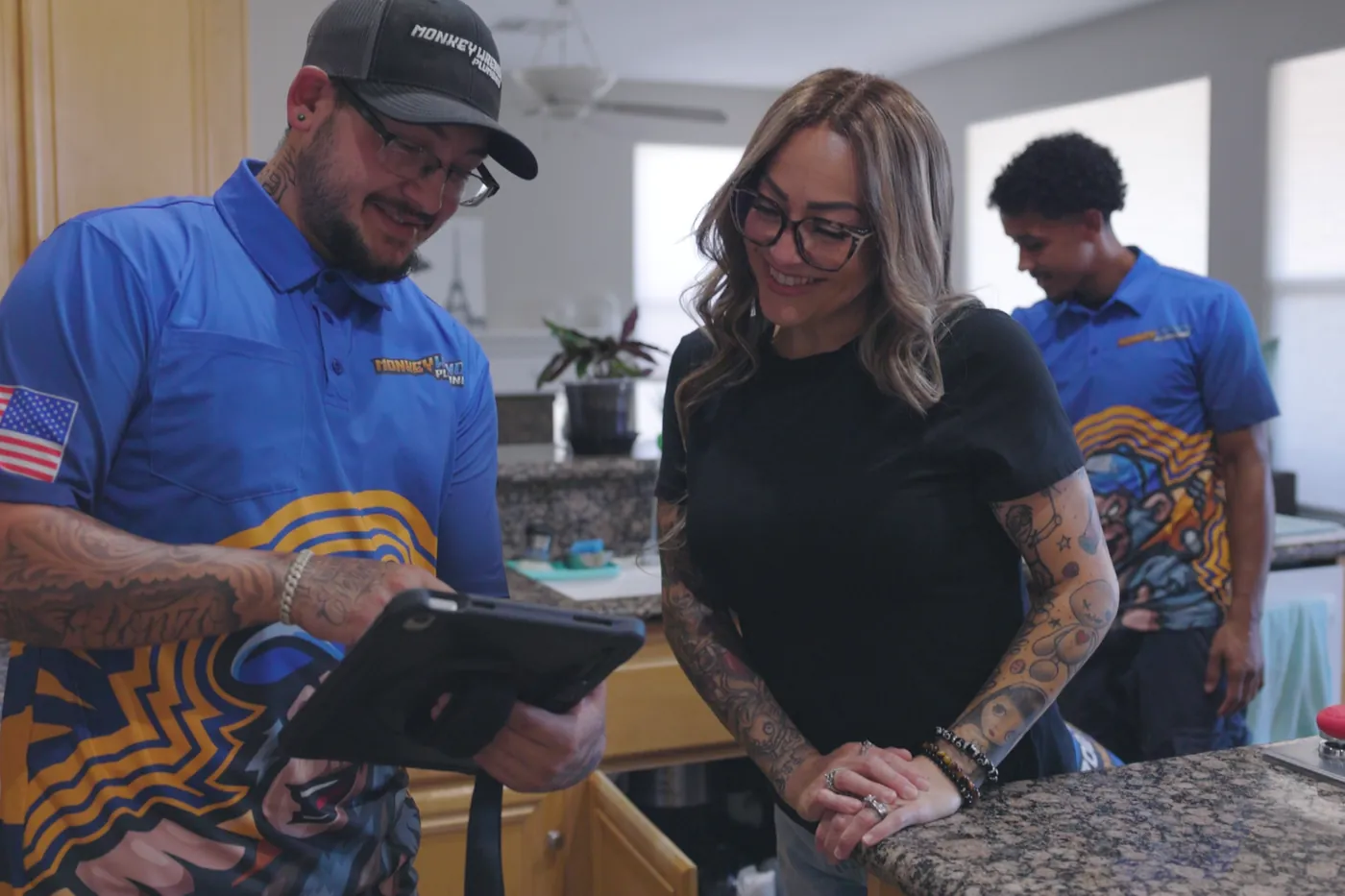 A Monkey Wrench technician going through a written plumbing quote with a homeowner at the kitchen counter