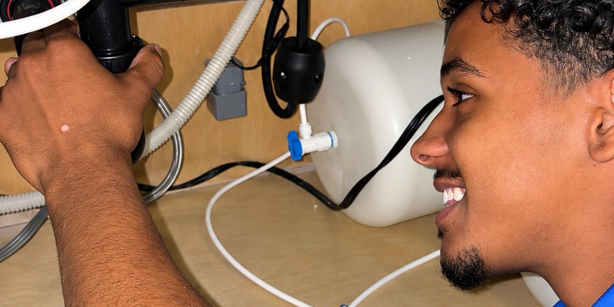 A Monkey Wrench technician working on the waste pipe under a Las Vegas kitchen sink